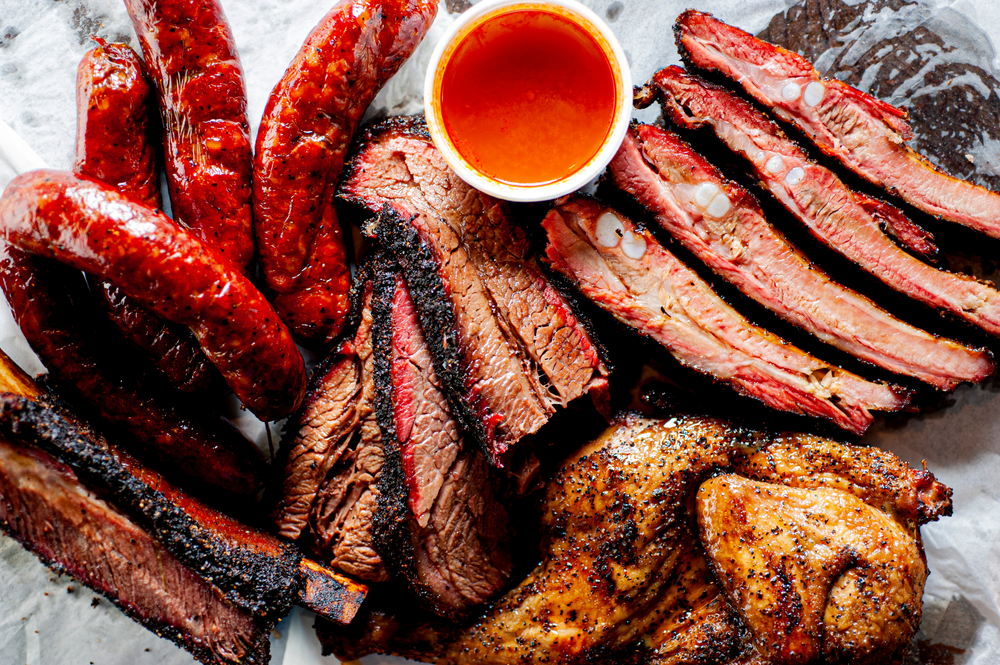 Brisket, pork ribs, beef ribs, chicken, pork sausage. BBQ. Barbecue meat platter with classic bbq sides Mac n cheese, cornbread, coleslaw and beer. Classic traditional Texas meats and side dishes.