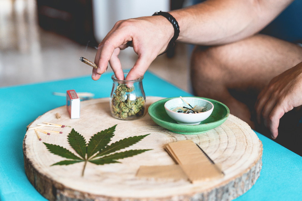 Young person smooking marijuana joint - Cannabis, stoner and weed concept - Main focus on left hand