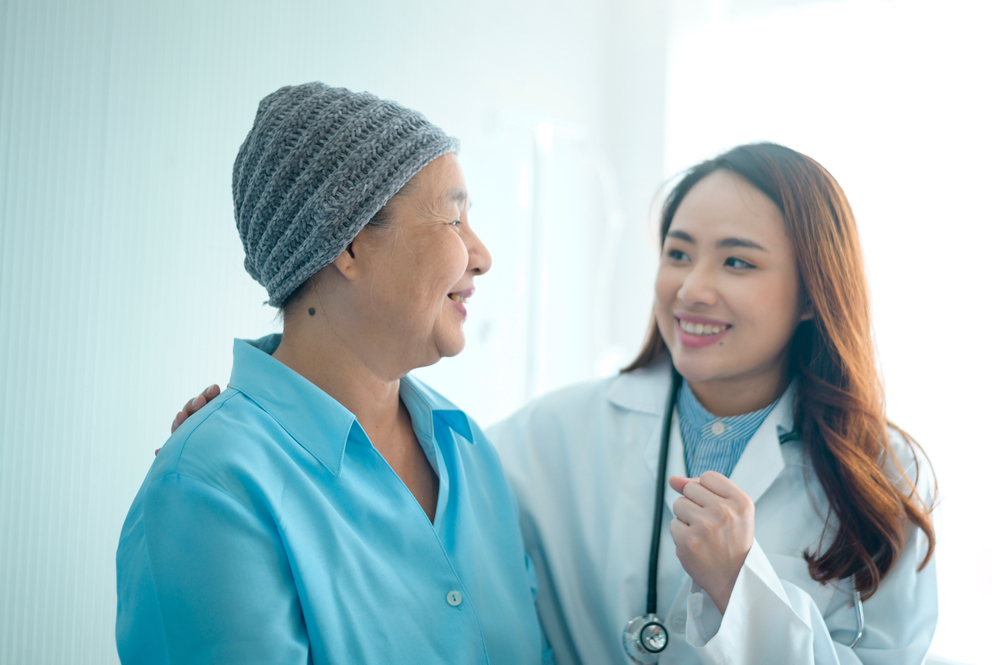 A cancer patient woman wearing head scarf after chemotherapy consulting and visiting doctor in hospital.