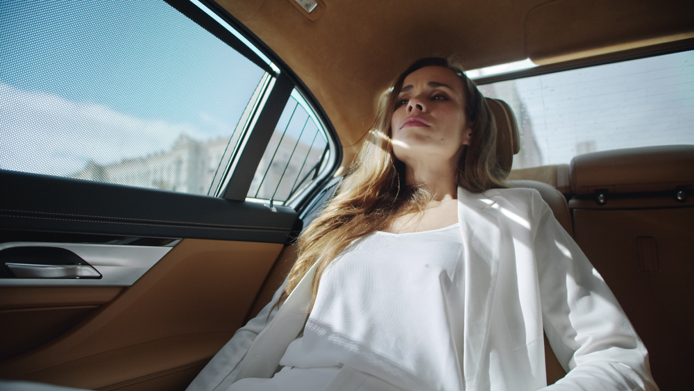 Portrait of exhausted business woman relaxing in salon of comfortable modern car. Tired businesswoman calming down in luxury automobile. Beautiful female ceo having rest in back seat of business car.