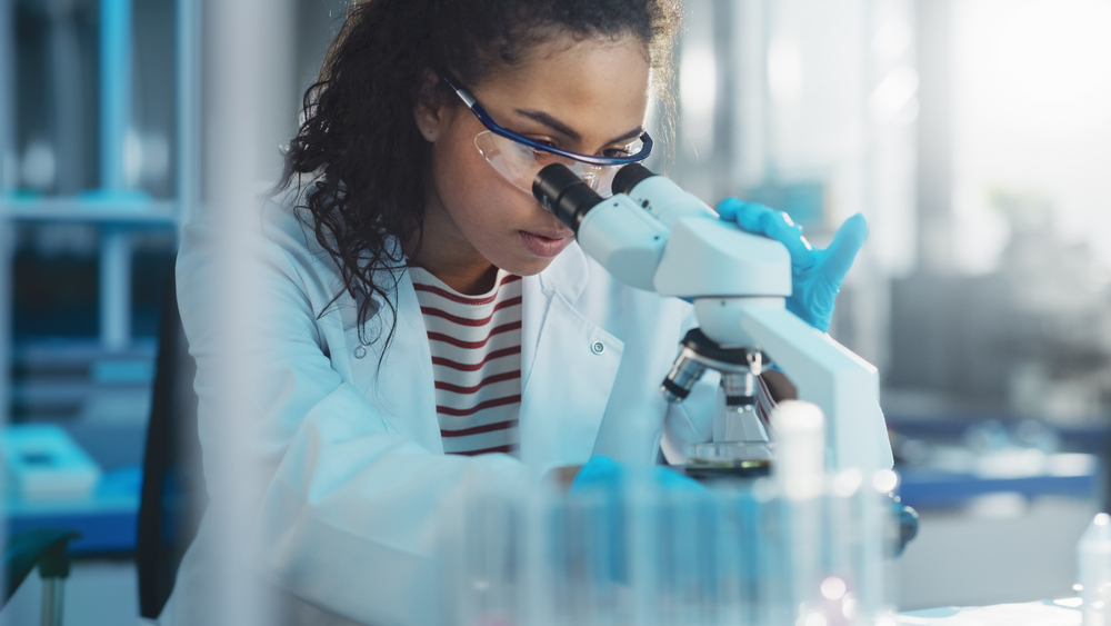 Medical Science Laboratory: Portrait of Beautiful Black Scientist Looking Under Microscope Does Analysis of Test Sample. Ambitious Young Biotechnology Specialist, working with Advanced Equipment
