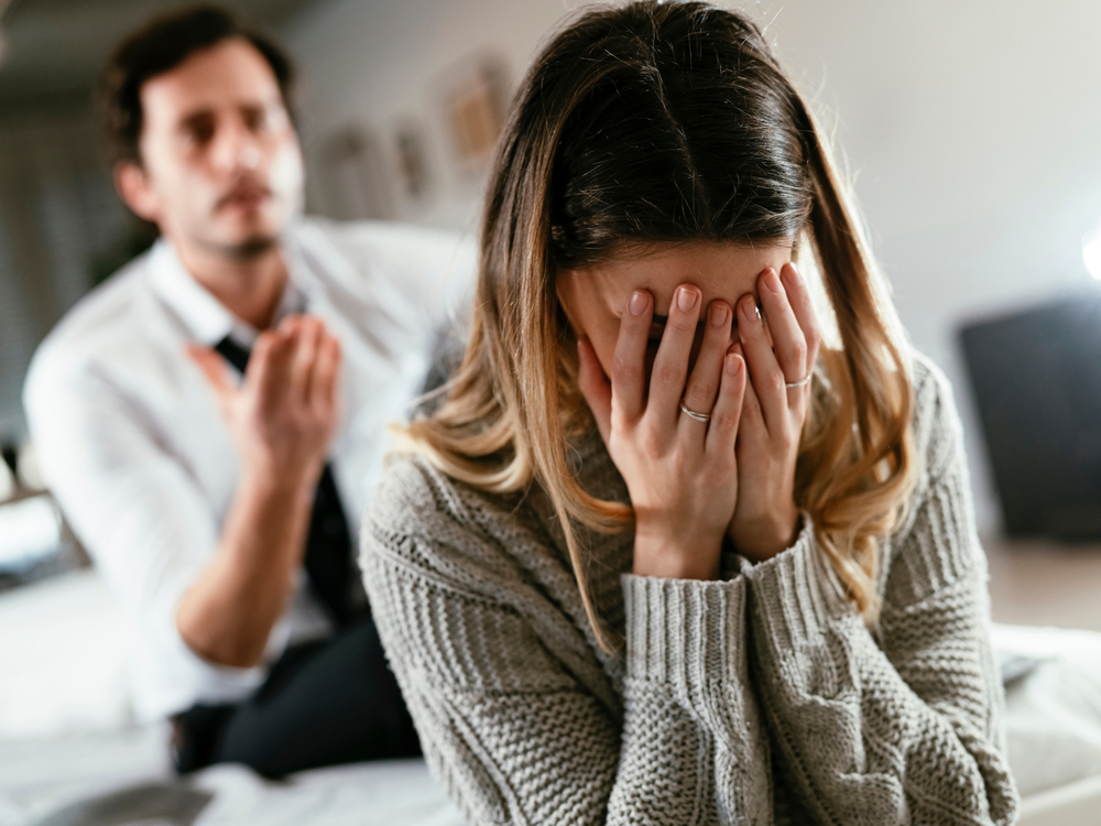 Boyfriend and girlfriend are arguing at home. Angry man is yelling at his sad girlfriend.
