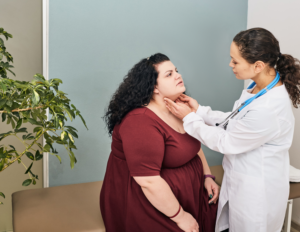 Doctor palpation of fat woman's neck for diagnostics of thyroid diseases and hypothyroidism.