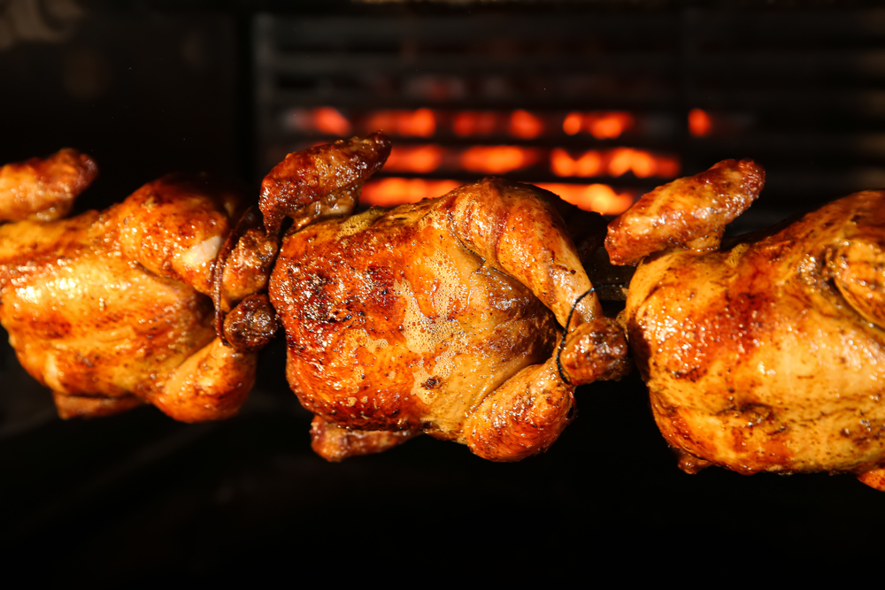 Grilling whole chickens in rotisserie machine, closeup
