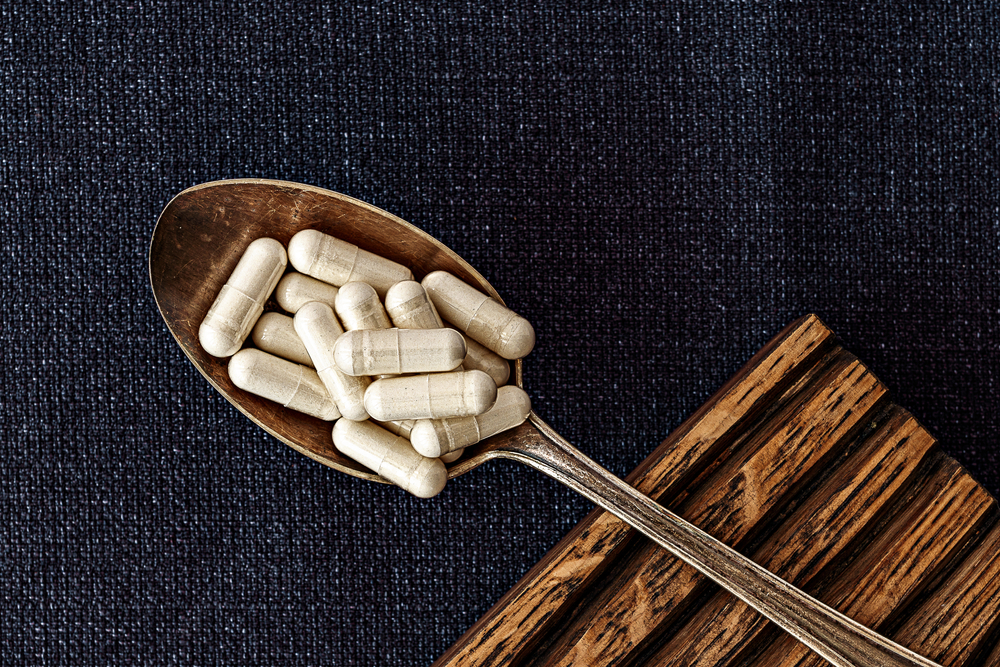 n-acetyl cysteine (NAC) supplement capsules on iron spoon. mental wellbeing and personal health concept
