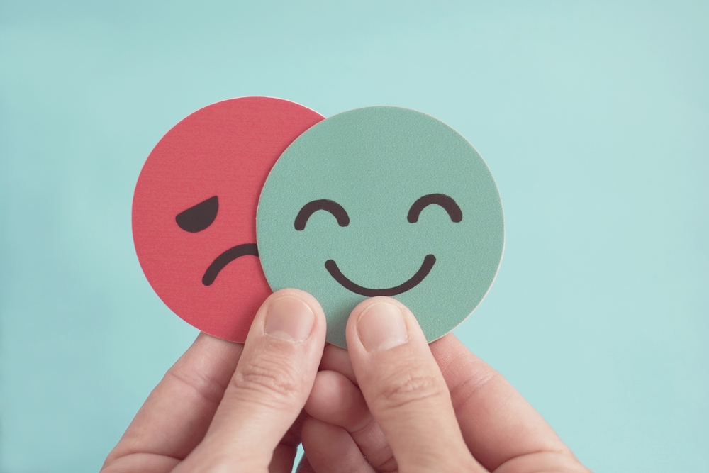 Hands holding happy and angry face paper, feedback rating , customer review, Emotional intelligence, balance emotion control,mental health assessment, bipolar disorder concept
