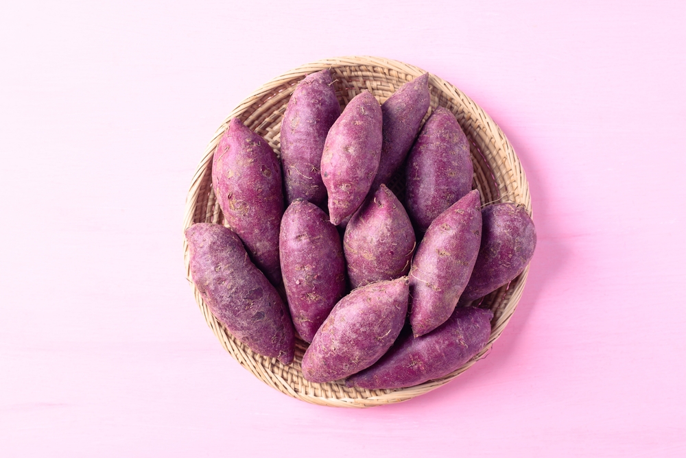 Plate with slices of fried purple potatoes, lemon and sauce on light background