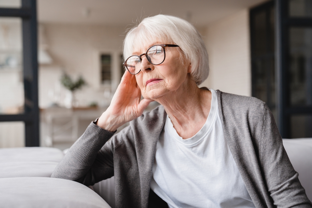 Sad tired ill sick lonely disappointed caucasian old elderly senior woman grandmother sitting on the sofa couch, feeling nostalgy, pain, missing grandchildren, bankruptcy, fraud at home
