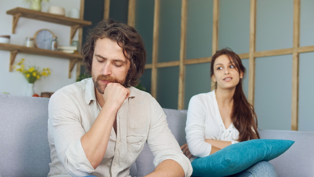 Couple Quarreling Sitting on the Couch at Home, Boyfriend Screams Accusing Girlfriend. Relationship Problems by Reason of Disagreement. The Man and Woman are Arguing. Young Woman Feeling Lonely.
