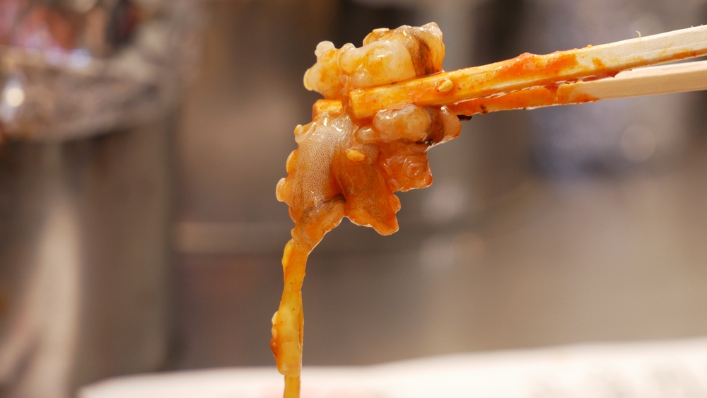 A Close Up Shot of Sannakji (Sliced Raw Octopus), A Korean Street Food Between A Chopstick