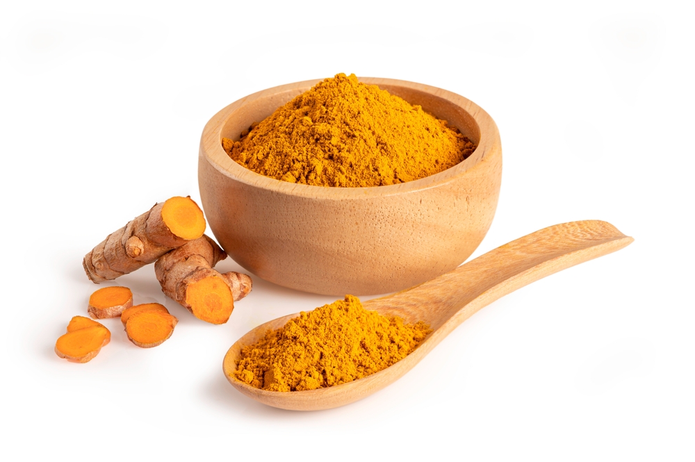 Turmeric powder in wooden bowl and spoon isolated on white background.
