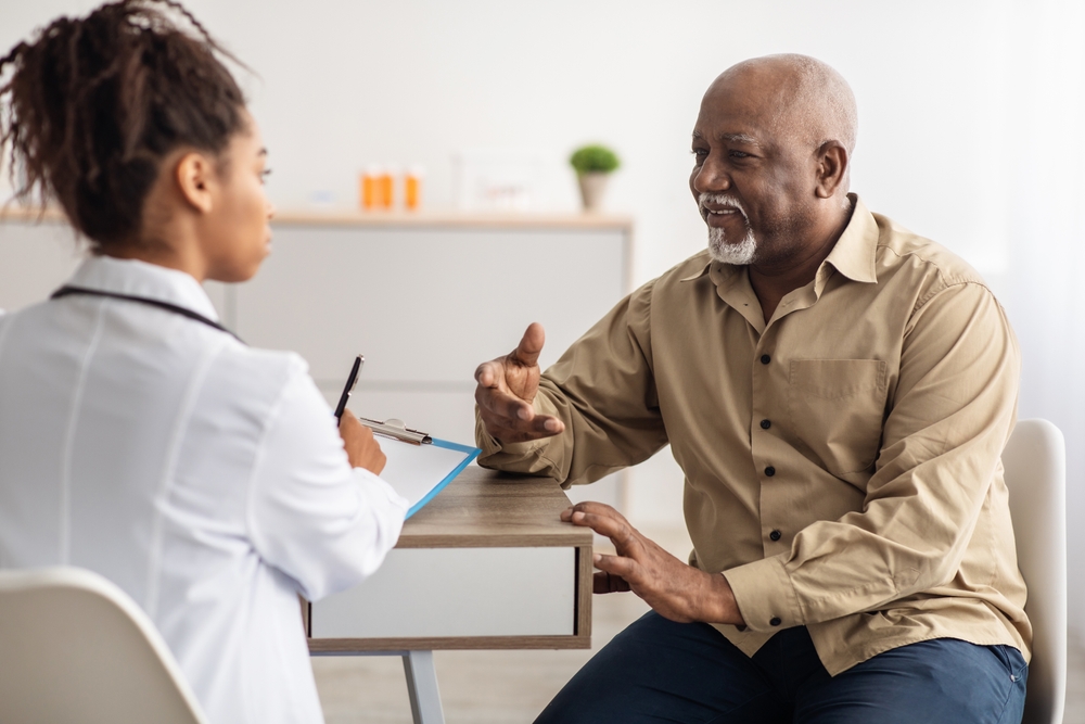 Healthcare, Geriatric Medicine, Medical Check Up. Senior man visiting doctor telling about health complaints, female gp or nurse writing personal information, filling form listening to elderly patient