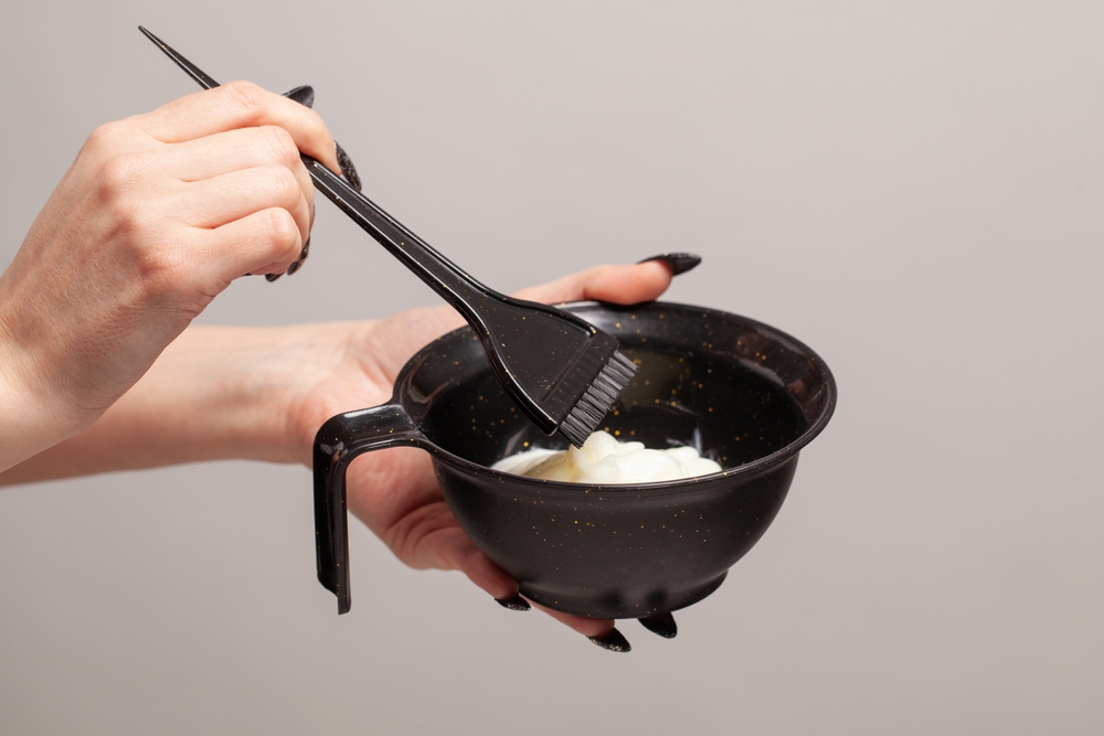 Hairdresser holding bowl with hair dye closeup
