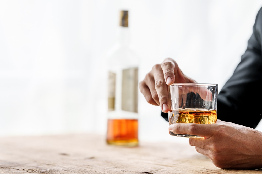 Sad depressed addicted drunk guy, Alone asian man drinker alcoholic sitting at bar counter with glass drinking whiskey.