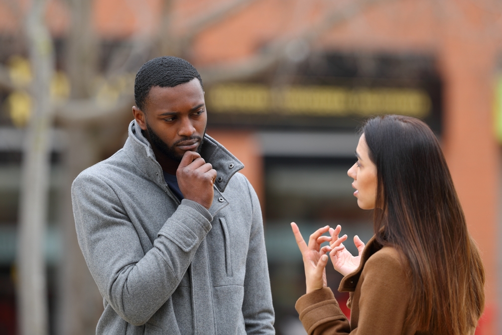 Suspicious man listening a woman talking in winter in the street