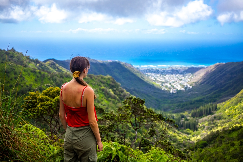 hiker girl enjoys the panorama of oahu island and honolulu in hawaii islands while climbing wiliwilinui ridge trail; hiking on green mountains in hawaii, holidays in hawaii
