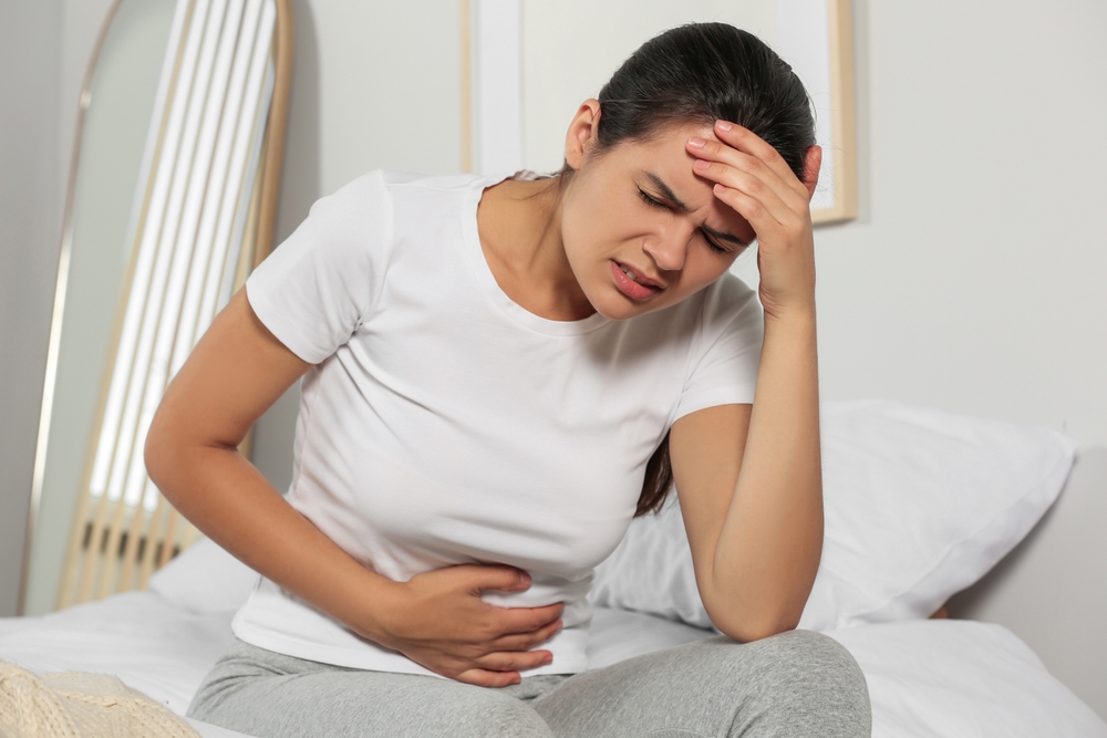 Young woman suffering from cystitis on bed at home
