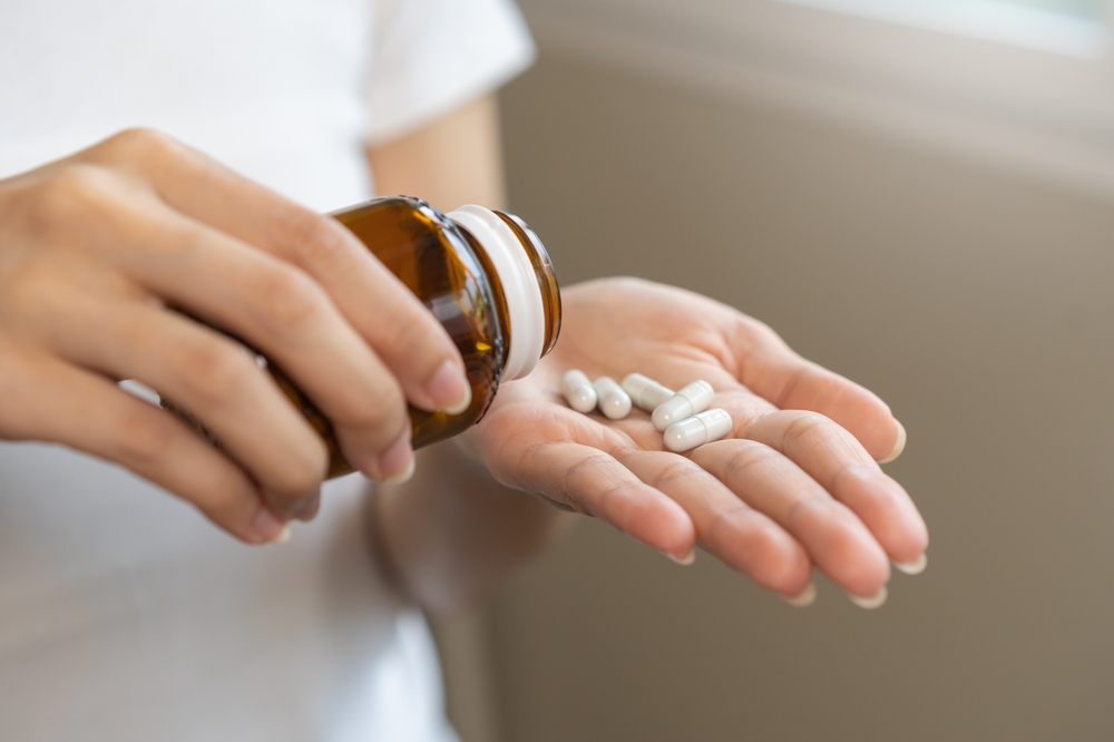 Dietary supplement or sick, asian young woman, girl hold pills, drugs medical tablet on hand pouring capsules from medication bottle, take vitamin for treatment for skin, hair at home, healthcare.
