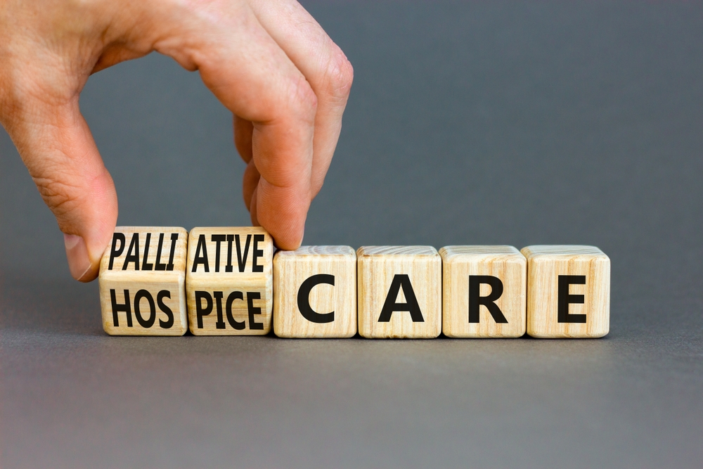 Palliative or hospice care symbol. Concept word Palliative care Hospice care on wooden cubes. Doctor hand. Beautiful grey table grey background. Medical palliative or hospice care concept. Copy space.
