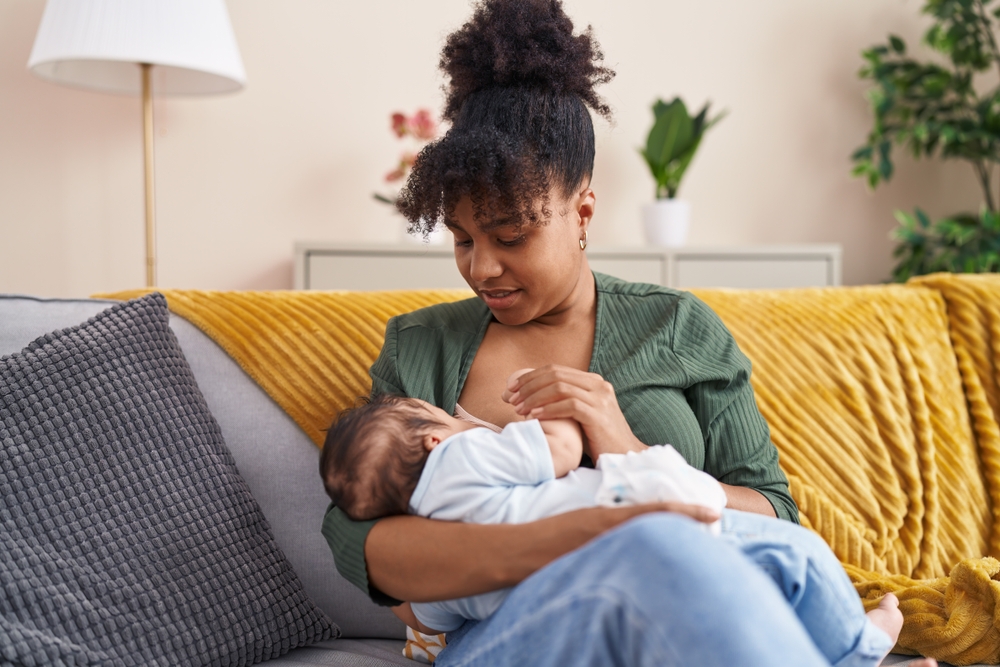Mother and son sitting on sofa breastfeeding at home 1