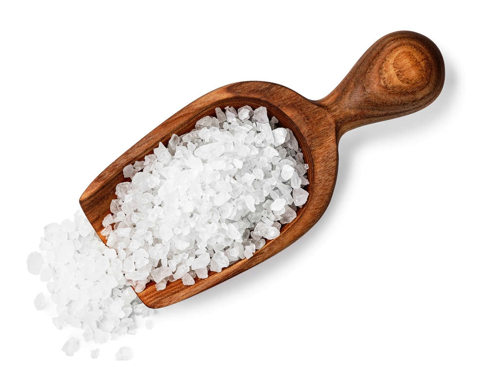 sea salt crystals in wooden scoop isolated on white background top view