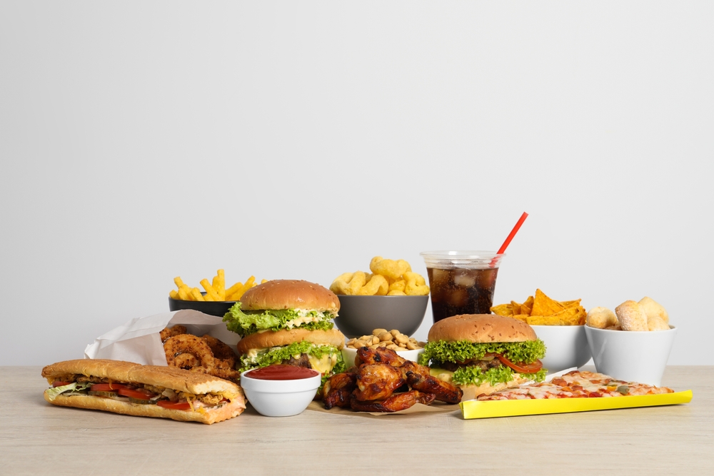 French fries, burgers and other fast food on wooden table against white background