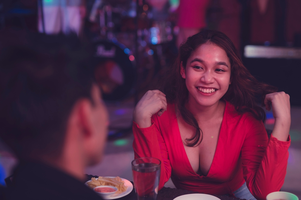 A bubbly young woman flips her hair as she flirts with the man she is interested with. Man and woman having fun on the first date. Beautiful lady shows her charm with a hair flip.
