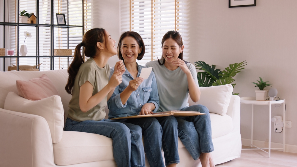 Recall the past life memories Happy time Mother's day grown up kid child joy fun look at old retro photo album with mature mum. Asia adult people middle age mom smile enjoy relax sitting at home sofa.
