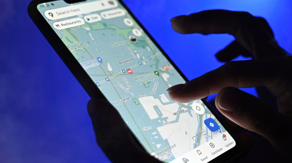 Poznan, Poland - 13 January: Girl using google maps app on a smartphone against blue background, close up view