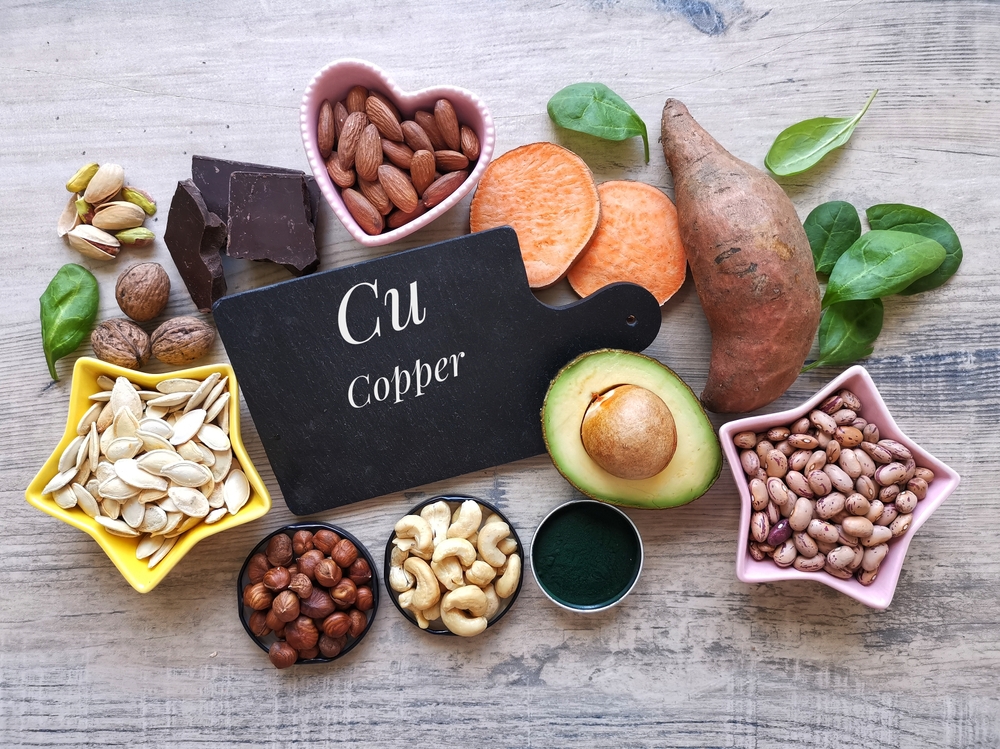 Copper high food. Natural food sources of copper with chemical symbol Cu. Assortment of fresh fruit, vegetable, nuts, seeds high in copper. Dark chocolate, avocado, spirulina, nut, seed, sweet potato