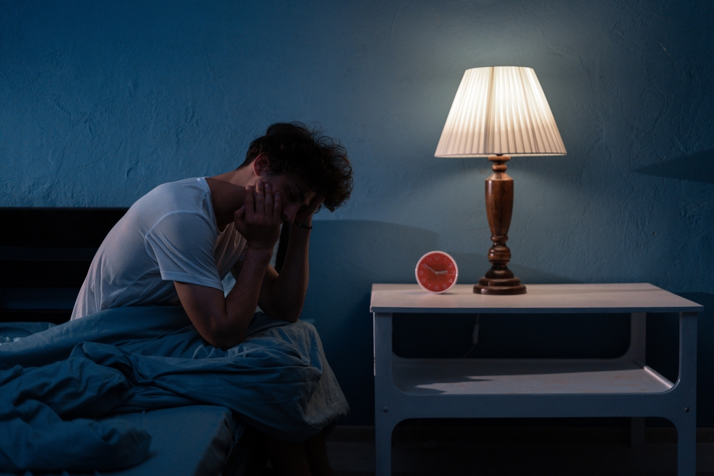 Sleepless, man suffering from insomnia, sleep apnea or stress. Tired and exhausted guy. Headache or migraine. Awake in the night. Frustrated person with problem. Copy space
