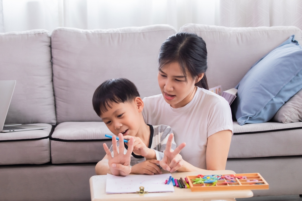 Young single mother teach little preschool age son to count explain math basics, doing homework together on holidays. Smart child boy prepares for school learn mathematics. education concept.
