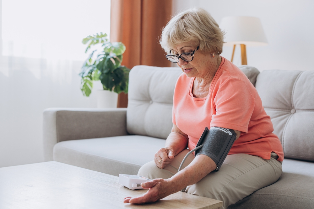 Senior woman with hypertension measuring blood pressure herself at home. Sad Mature lady measure blood pressure using tonometer. Everyday health check-up