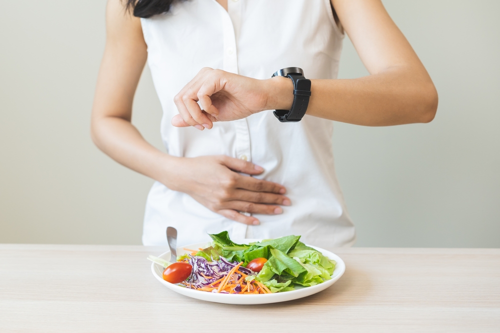 Composition with cutlery, plate and alarm clock on color background. Diet concept