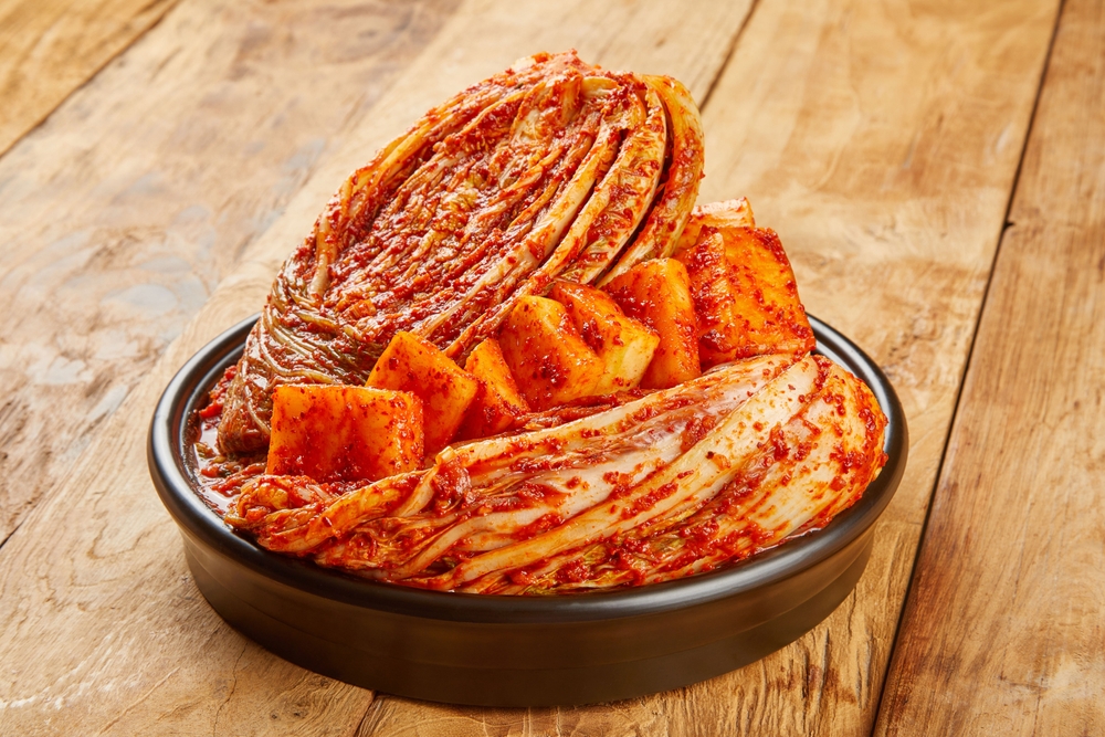 Cabbage kimchi and radish kimchi are served on a ceramic plate.
