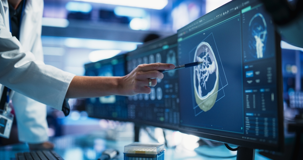 Modern Cancer Research Medical Center: Anonymous Doctor Pointing At Desktop Computer Monitor With 3D Software Visualizing Human Brain Based On CT Scan. Neurologist Looking For Tumor In Patient's Brain
