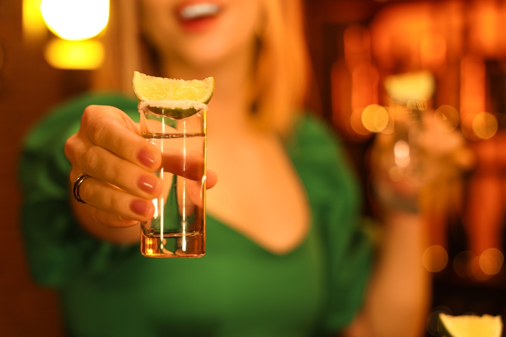 Young woman with tequila shot in bar at night, closeup