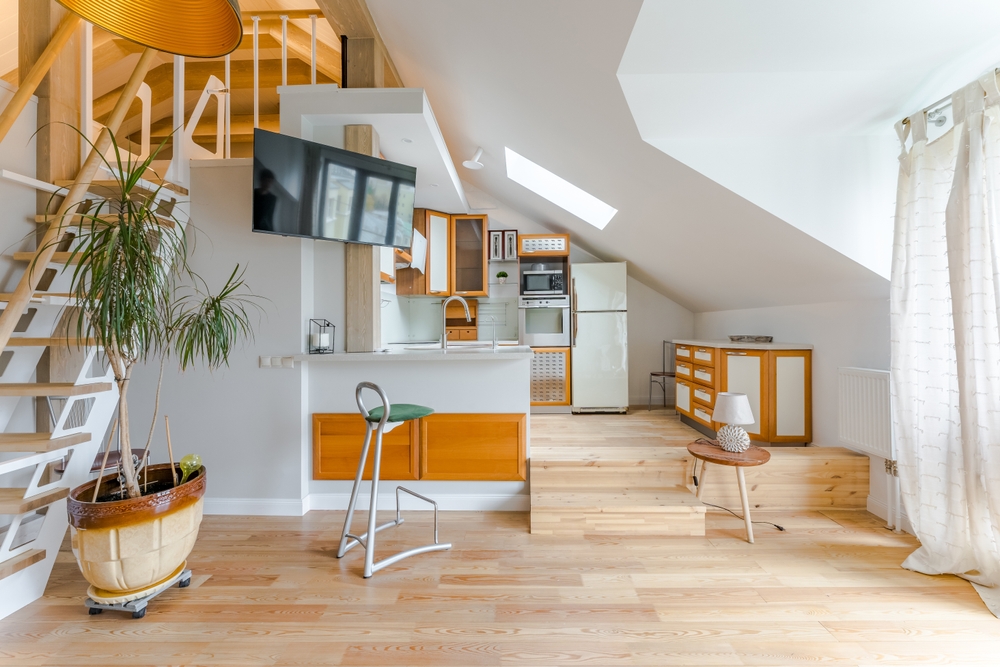 Moscow, Russia - August 13, 2023: The interior of the spacious living room and kitchen . A bright living room in the penthouse with a panoramic window and a staircase to the second floor .
