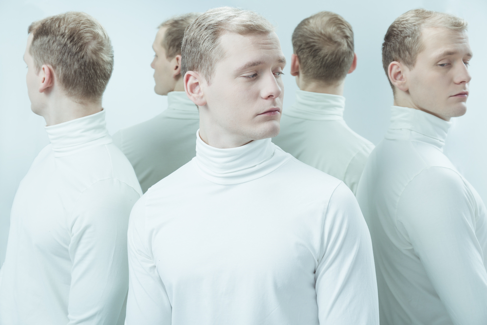 Young patient of mental hospital standing in light interior, duplicated image