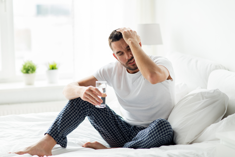 people, bedtime and rest concept - man in bed with glass of water at home