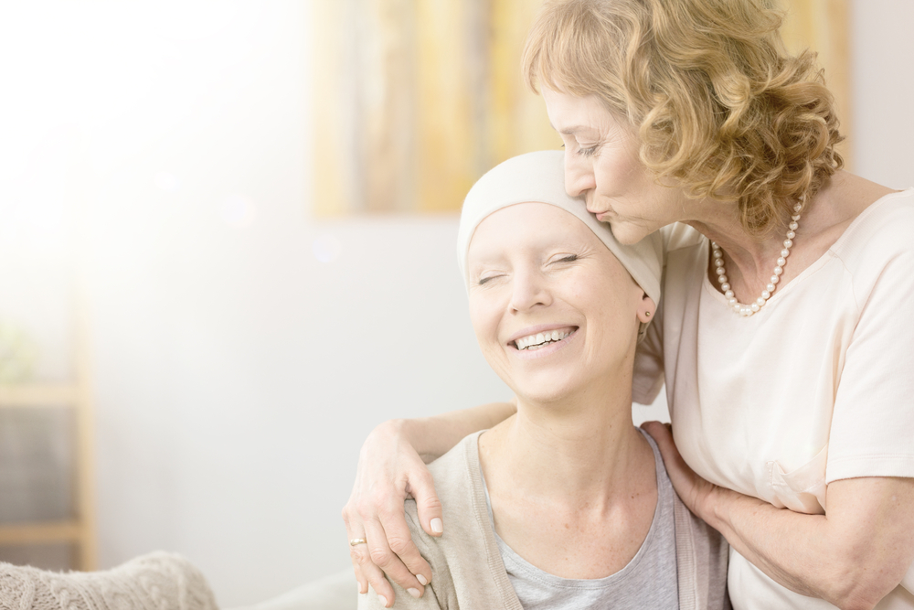 Elderly woman kissing happy cancer survivor's temple, comforting her friend