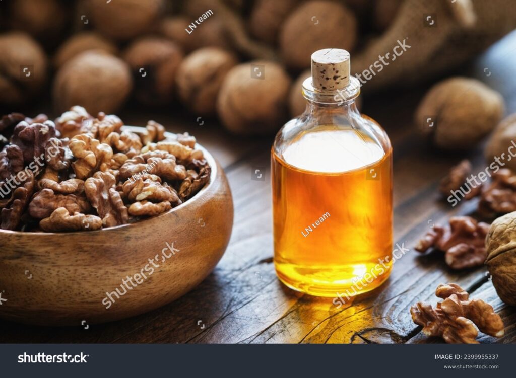 Wooden bowl of walnuts and bottle of essential nut oil on kitchen table.