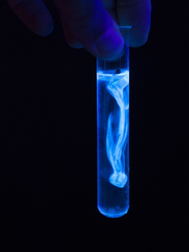 A neon blue glow-in-the-dark test tube. Black background. 