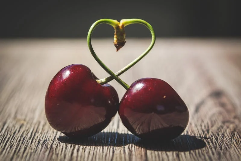 two cherries with their stems bent into a heart