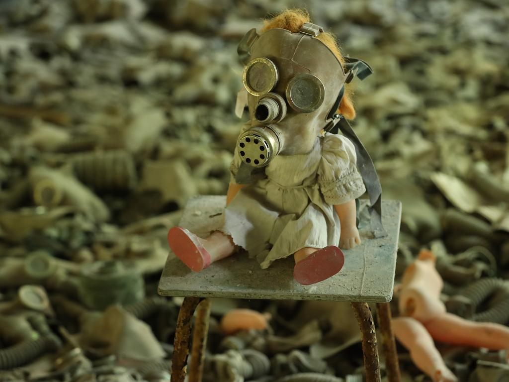 A doll, likely arranged by a tourist, dressed with a gas mask sits on a chair among hundreds of gas masks lying on the floor of abandoned School Number 3 in the ghost town of Pripyat. 