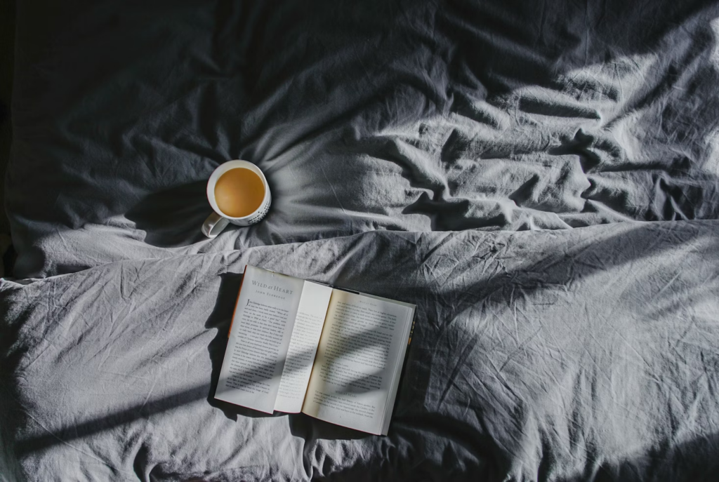A mug and a book on a bed