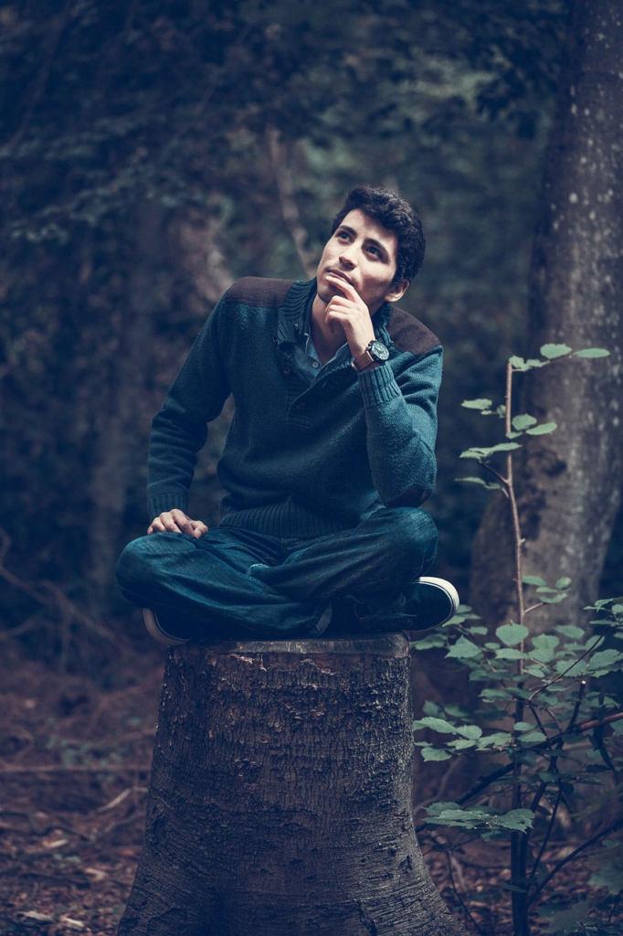 person sitting on a tree stump thinking