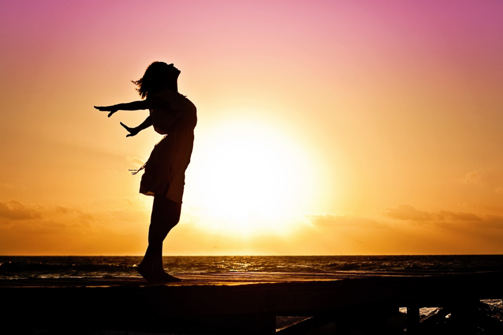 woman breathing in deep by the ocean at sunrise