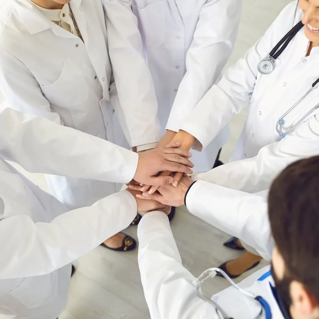 A team of doctors with their hands together in solidarity. 
