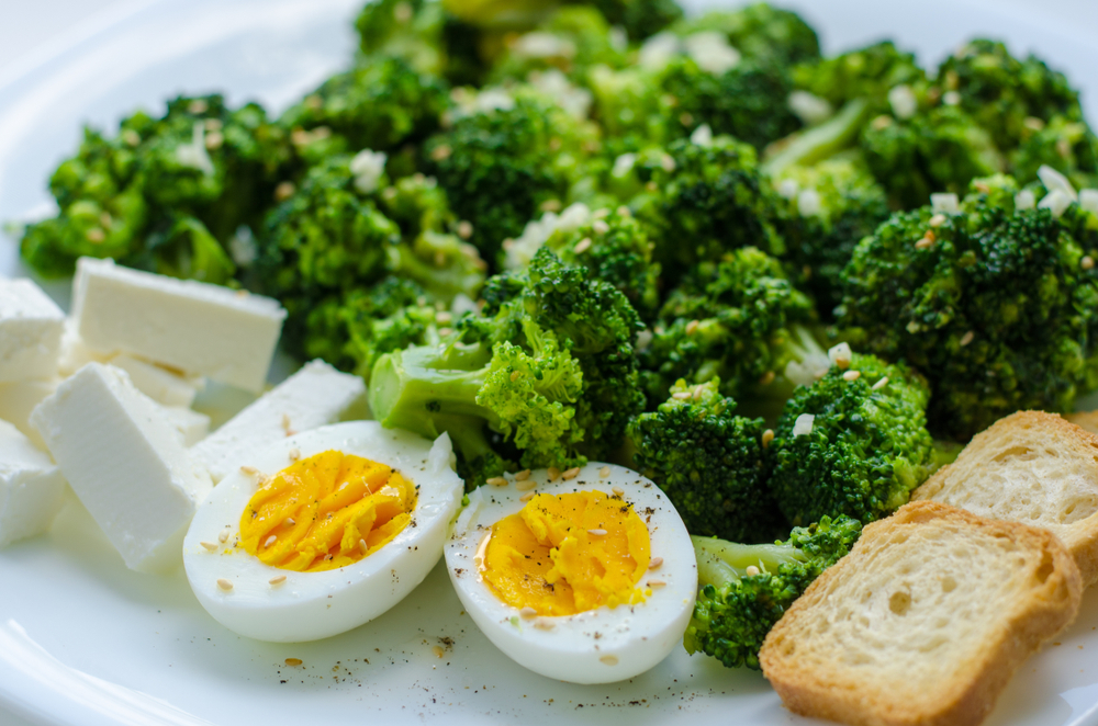 Healthy breakfast or lunch close up on white plate with boccoli,feta cheese,boiled egg and bread creckers. Proper nutrition concept. top view
